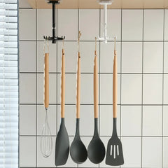 Set of four kitchen utensils with wooden handles hanging on a magnetic strip against a tiled wall.