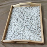 Wooden tray with a mosaic glass top on a beige surface