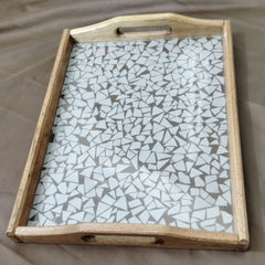 Wooden tray with a mosaic glass top on a beige surface